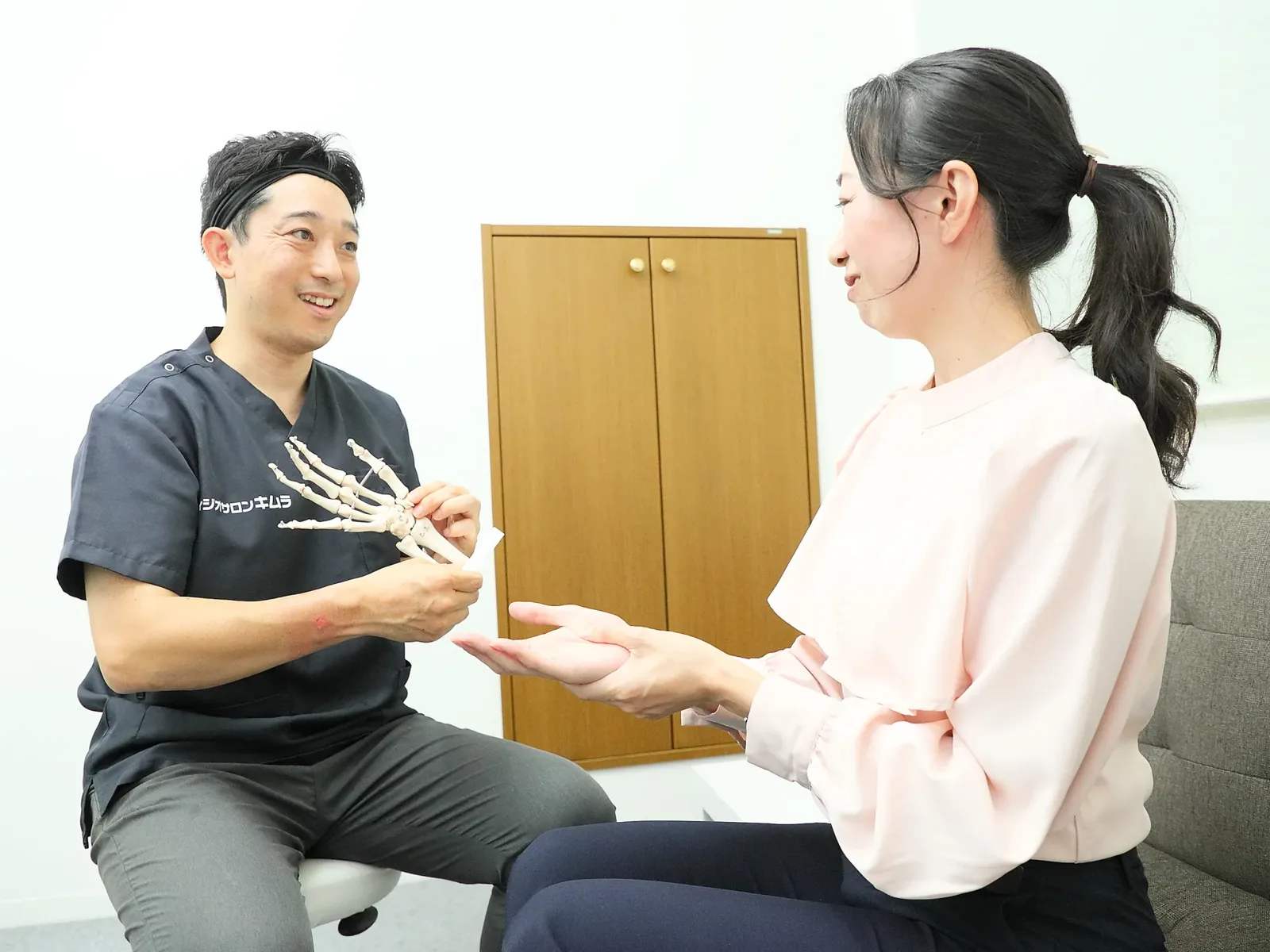 フィジオサロンキムラで、手の骨の模型を使って説明する木村晋一朗
